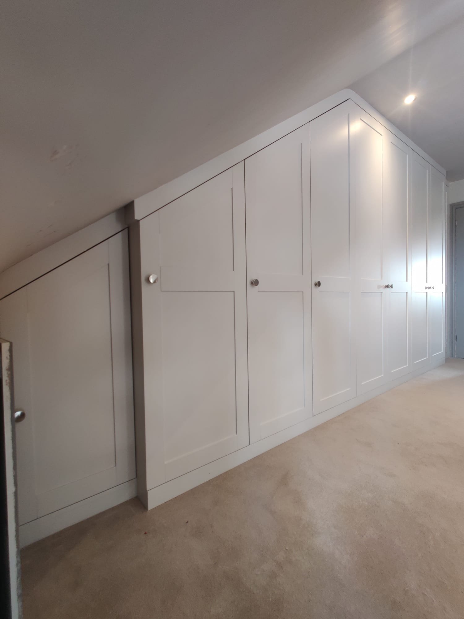Floor-to-ceiling fitted wardrobes hand-sprayed in a flawless soft white